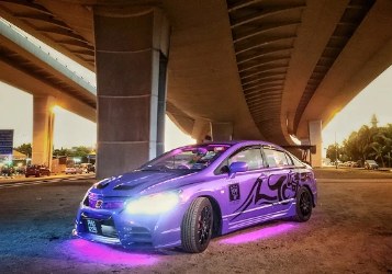 Purple modified saloon under a flyover